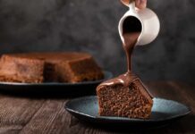 A slice of chocolate cake being drizzled with chocolate sauce