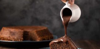 A slice of chocolate cake being drizzled with chocolate sauce