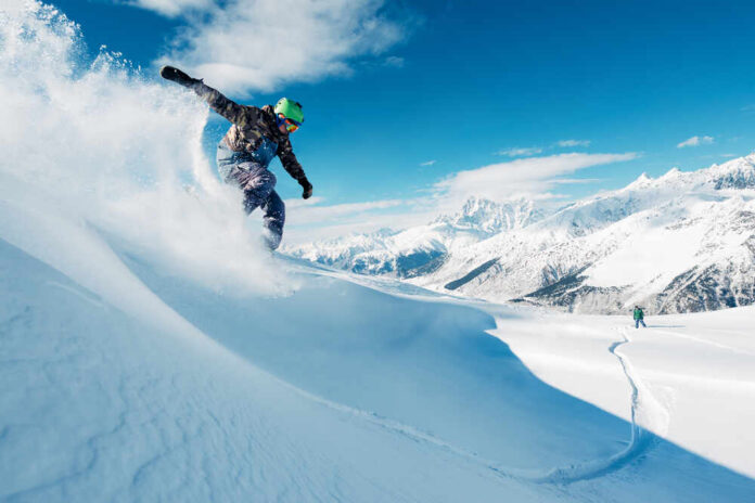 shutterstock_593831324.jpg Snowboarder carving through fresh snow on a mountain slope