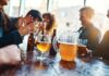 Group of friends enjoying drinks at a bar with a pitcher of beer on the table