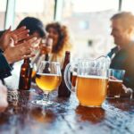 Group of friends enjoying drinks at a bar with a pitcher of beer on the table
