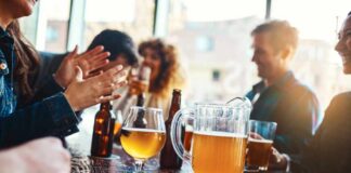 Group of friends enjoying drinks at a bar with a pitcher of beer on the table