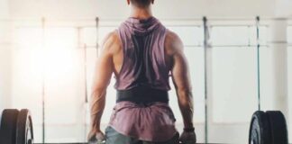 A muscular person preparing to lift a barbell in a gym setting