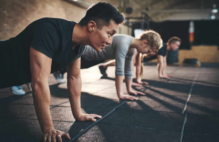 Group of individuals performing push-ups in a gym