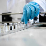 A healthcare professional in a lab preparing vaccine vials