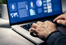 Close-up of hands typing on a laptop with data visualizations on the screen