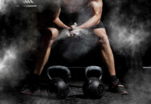 Gym Return Mistakes That Lead to Injury Athlete preparing to lift kettlebells in a gym with chalk dust in the air