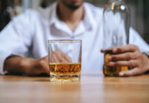 A man holding a whiskey glass and a bottle in a bar setting