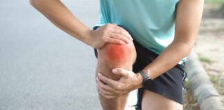 Athlete holding their knee in pain while exercising outdoors