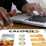 Surprising Diet Tweak Slashes Cancer Risk Person using a calorie counter app on a tablet while working on a laptop