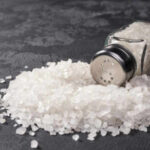 Salt in Food: The Diet Myth Ruining Health A glass salt shaker tipped over with salt spilling out