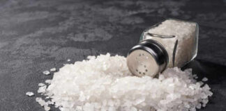 A glass salt shaker tipped over with salt spilling out