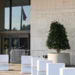 Entrance of the Hubert H. Humphrey Building with a decorative plant and a flag visible