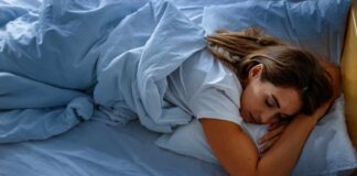 A woman sleeping peacefully on a bed with blue sheets