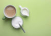 Caffeine’s Double-Edged Role in Inflammation A cup of coffee, a bowl of sugar, and a creamer on a green background