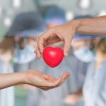 Mayo Shocker: 0% Alcohol Relapse After Transplant Two hands exchanging a red heart symbol in a surgical setting