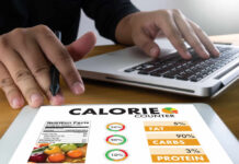 Protein Myth Wrecking Your Diet Person using a calorie counter app on a tablet while working on a laptop