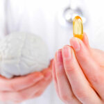 FTC Slams “Memory Pill” Hype A medical professional holding a brain model in one hand and a yellow supplement capsule in the other