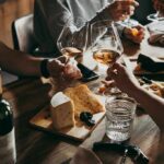 How Moderate Drinking Tricks Your Brain Hands toasting wine glasses over a cheese board