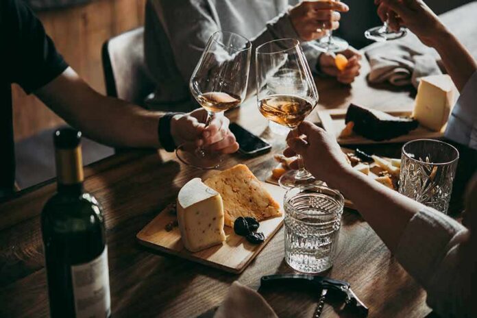 Hands toasting wine glasses over a cheese board
