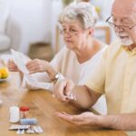 Alzheimer’s Curveball: Heart Drug Nudges Memory Older man taking pills at a table while woman reads instructions