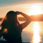 Silhouette of a person looking at a sunset over water