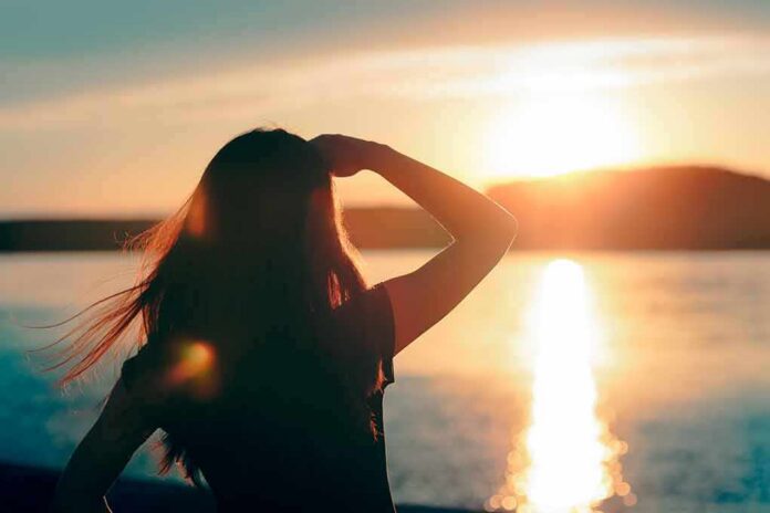 shutterstock_1011373993 Silhouette of a person looking at a sunset over water