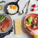 Breakfast spread with bacon, asparagus, eggs, avocado, berries, nuts, and cheese