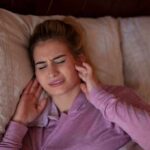 How AI Can Spot Cavities Years Early woman in bed covering ears with a pained expression
