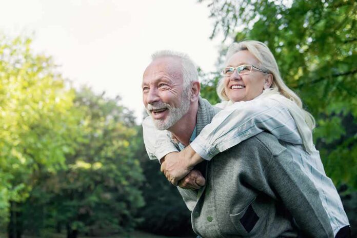shutterstock_742276540 older couple smiling during piggyback ride in a park