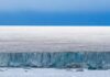 Ice cliff along a polar glacier under a blue sky