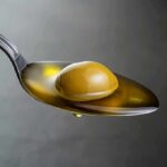 Green olive on a spoon with olive oil