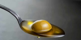 Green olive on a spoon with olive oil