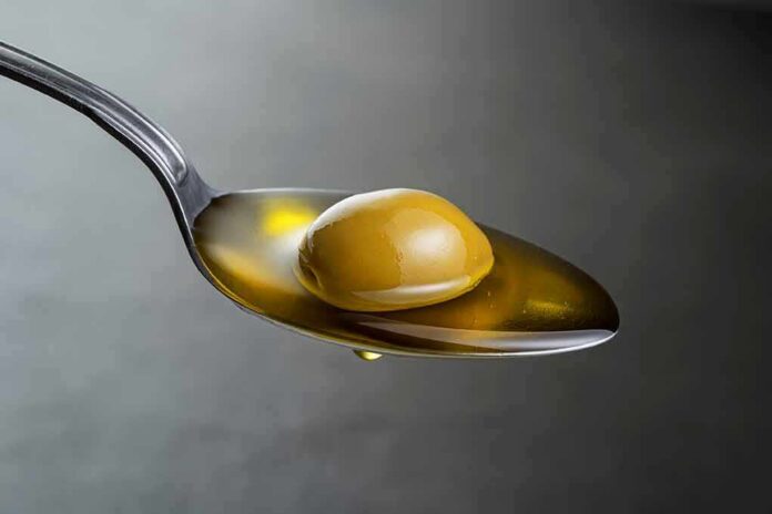 Green olive on a spoon with olive oil