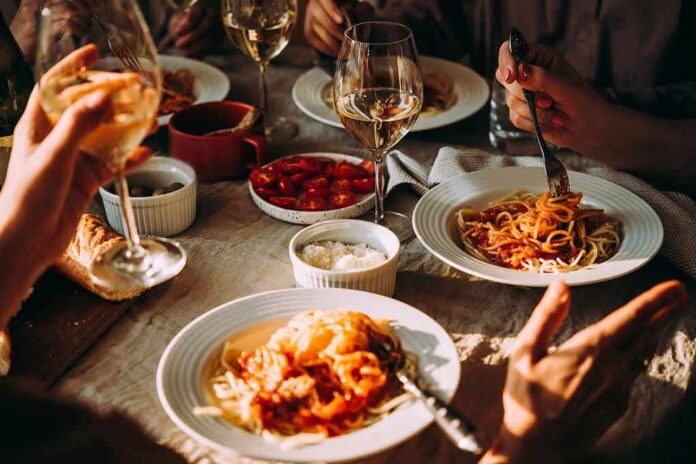 shutterstock_1191840604 Pasta dinner with wine on a sunlit table