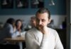man sitting alone in a cafe looking to the side