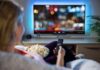 How Modern Living Changes Our Hormones From Birth Person sitting on a couch watching a movie on a TV with popcorn in hand