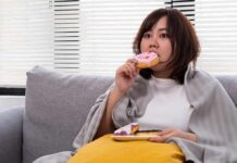 Alzheimer’s Risk Gene Meets Junk Food Woman on couch eating a pink frosted donut