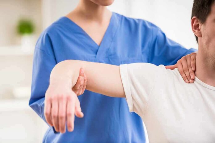 shutterstock_276800936 Physical therapist guiding a patient's arm during shoulder exercise