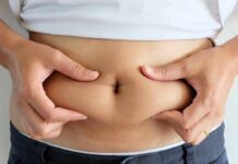 Belly Fat Linked To Embarrassing Leak Risk person pinching belly fat at the waist