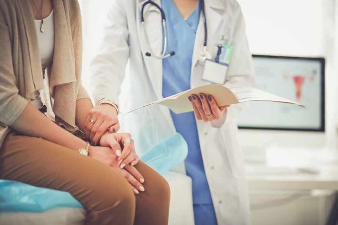 shutterstock_696188545 Doctor comforting patient while reviewing medical chart