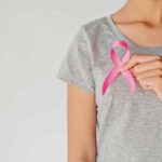 One Eating Shift, Big Cancer Risk Plunge Person holding a pink ribbon on a gray shirt