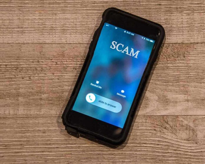 shutterstock_1252782130 Smartphone showing an incoming scam call on a wooden surface