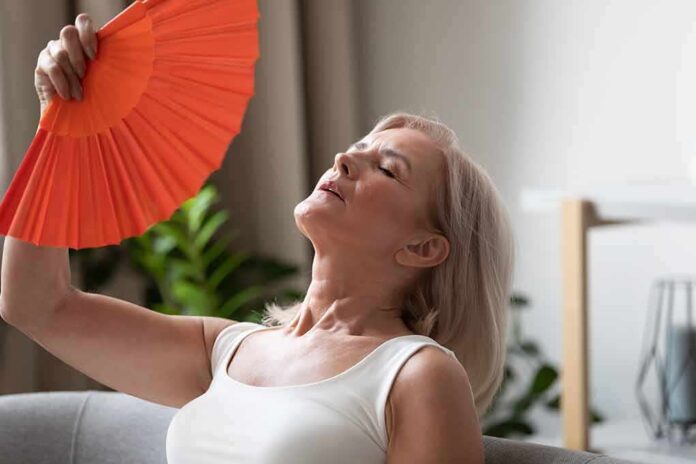 Woman fanning herself with an orange hand fan