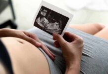 Pregnant person holding an ultrasound photo over their belly