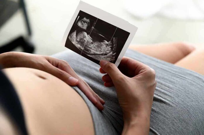 shutterstock_1717926007 Pregnant person holding an ultrasound photo over their belly