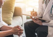 Doctor with clipboard talking to patient on a sofa